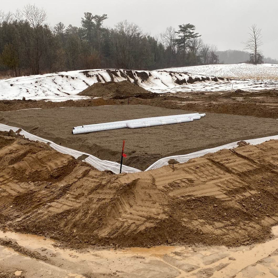 The installation of an above-ground septic system in a challenging site with a high water table and poor soil permeability.