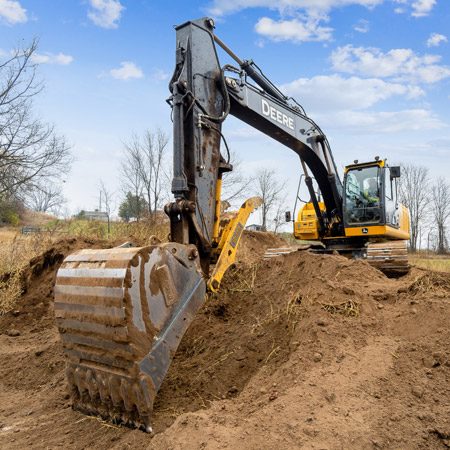 Excavation services are underway, with an excavator moving earth on a large undeveloped property.
