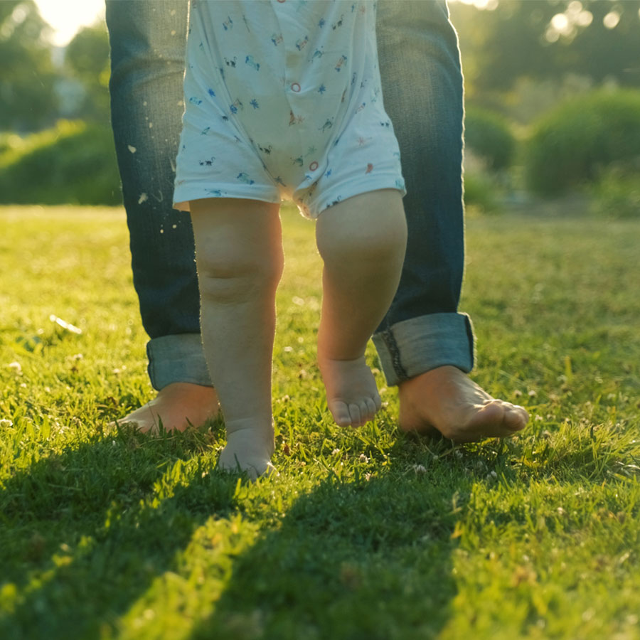 Family helps baby take first steps on clean lawn above a maintained septic system.
