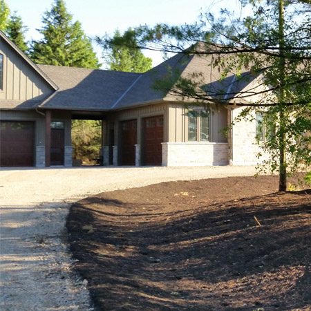 Grading service is in progress next to a driveway to control drainage on the estate property.